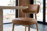 Close-up of a Savoca chair in Tawny leather at seat height: stitched seams on the seat and the back band