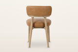 The back of the Savoca dining chair in Tawny leather on a warm white studio backdrop: the back band