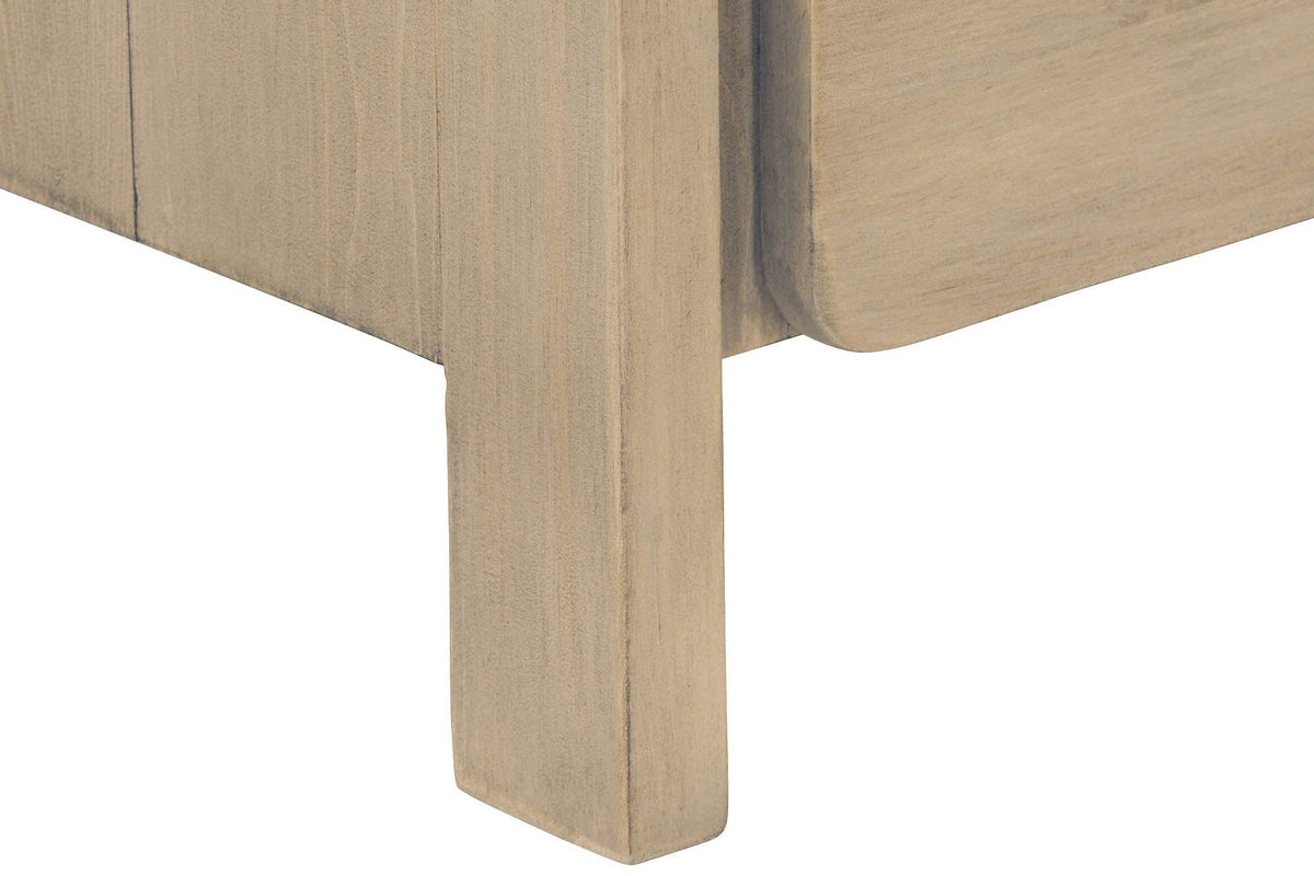 Close-up of a Scheggino square leg in pale reclaimed pine, under the planked side and the rounded corner of the lower drawer