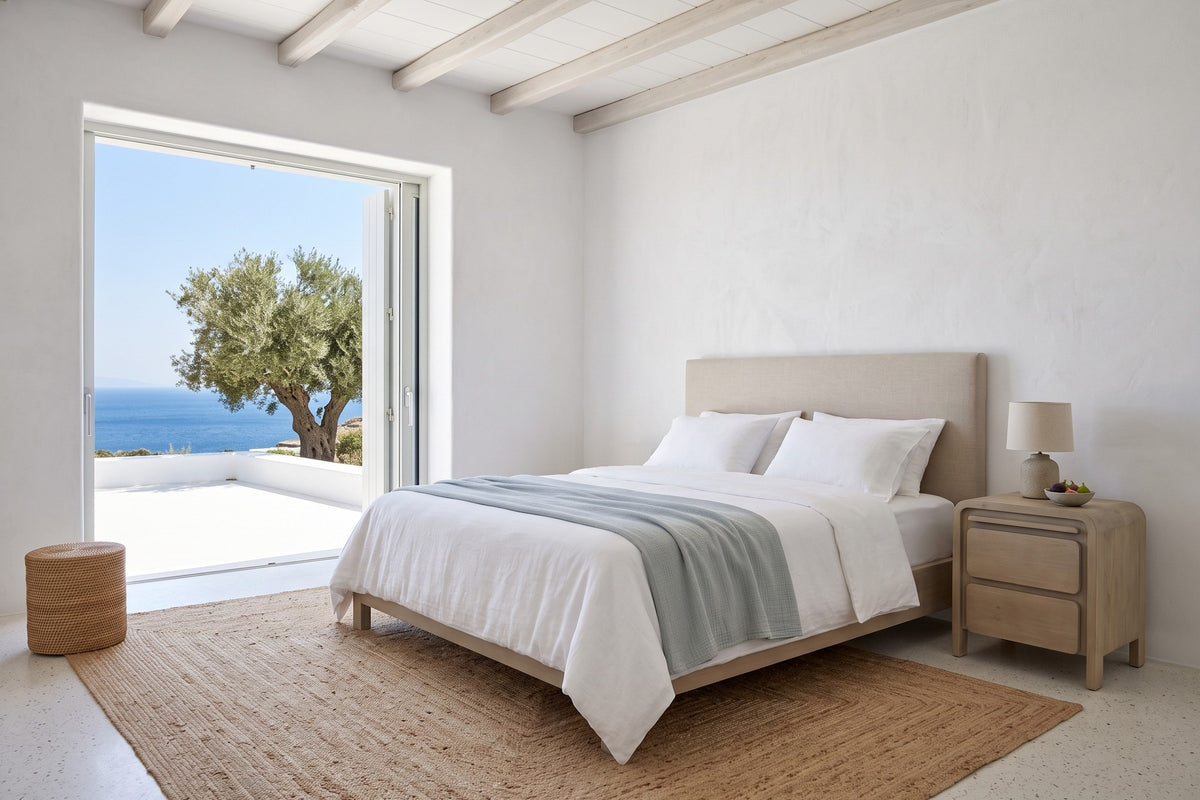 Scheggino nightstand in pale reclaimed pine at the right of the bed in a white Serifos villa bedroom, with juniper beams