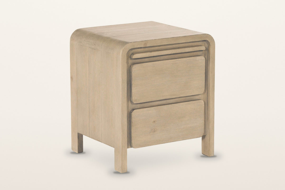 Scheggino nightstand in pale reclaimed pine, three-quarter view on a warm white studio backdrop: a waterfall top with rounded