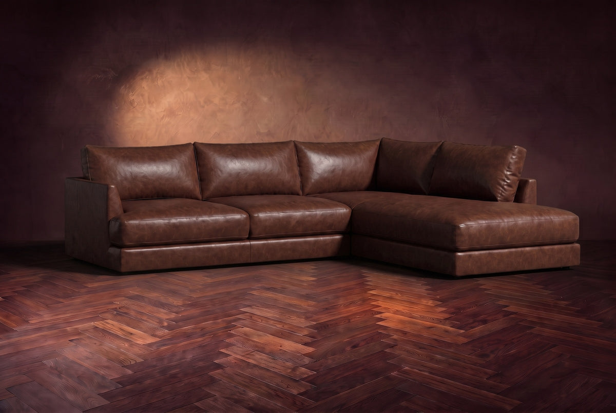 The Serena sectional in Burnished Chestnut distressed full leather on a walnut herringbone floor against a dark plaster wall, three-quarter view. Shown in Burnished Chestnut, Right bumper.