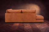 The Serena sectional in Tuscan Cognac distressed full leather on a walnut herringbone floor against a dark plaster wall, seen from the chaise side. Shown in Tuscan Cognac, Left bumper.