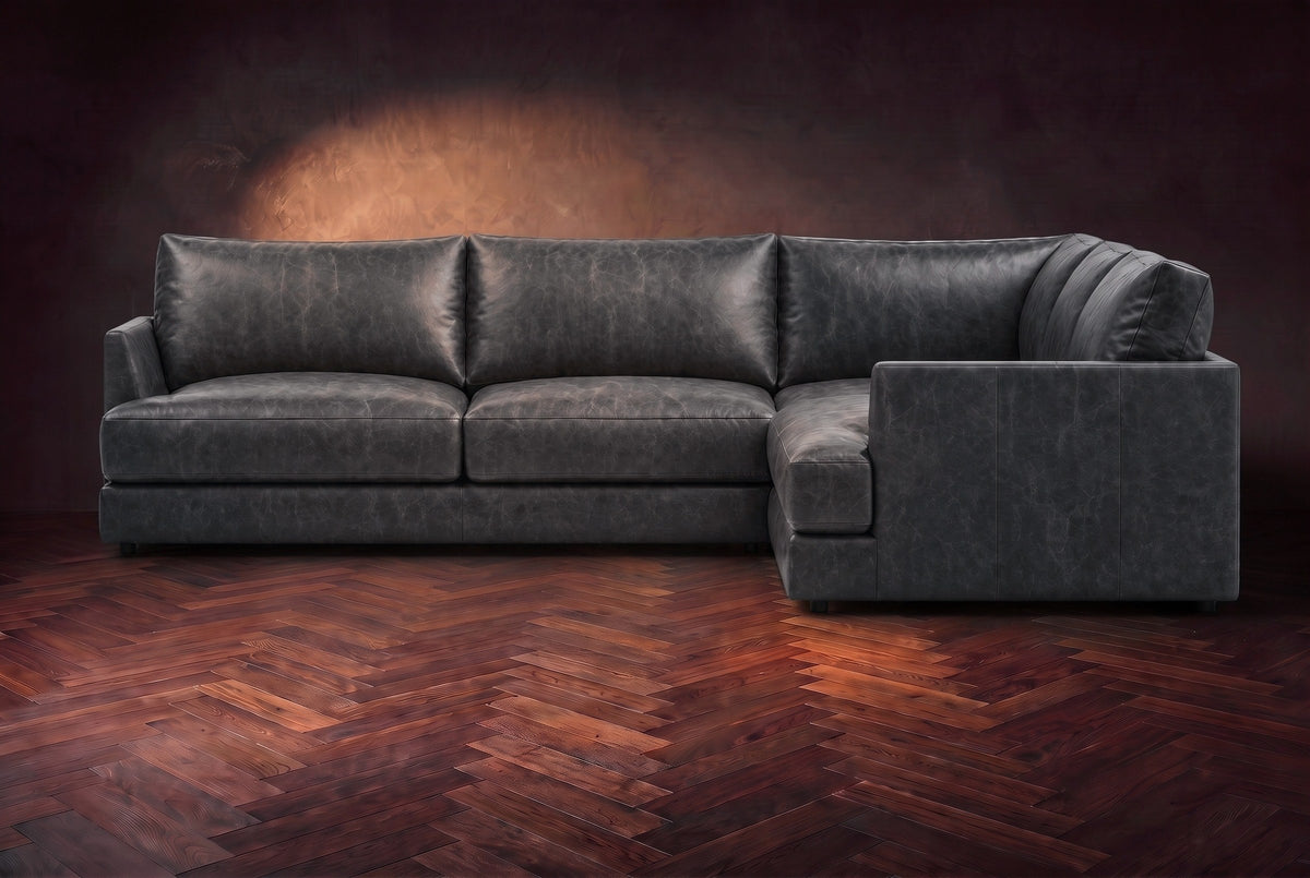 Serena corner sectional in Aged Slate on a walnut herringbone floor, seen from the front with the near side on the right.