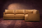 Serena corner sectional in Antiqued Caramel on a walnut herringbone floor, seen from the front with the near side on the right.