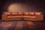 Serena corner sectional in Tuscan Cognac on a walnut herringbone floor, three-quarter view.