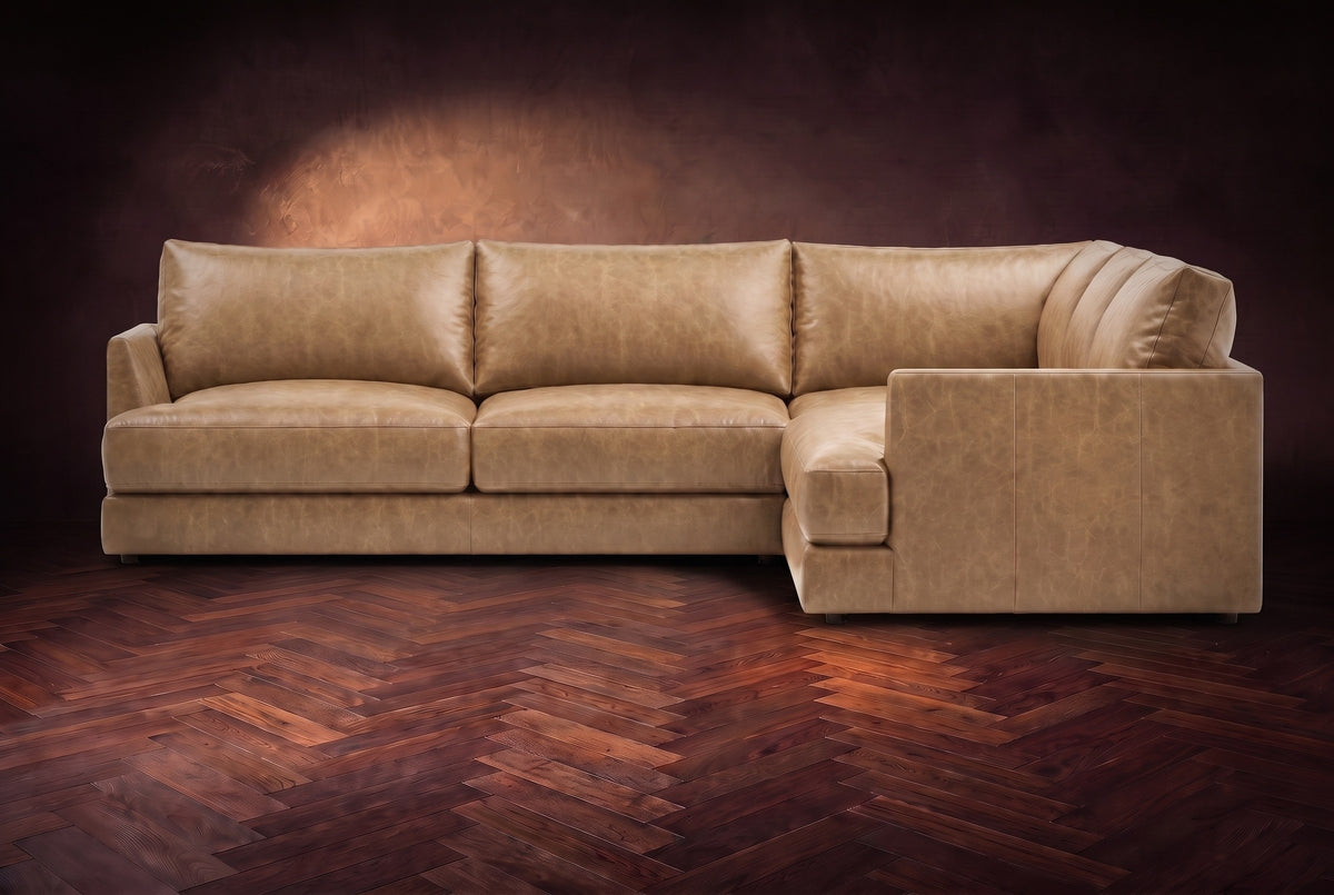 Serena corner sectional in Washed Sand on a walnut herringbone floor, seen from the front with the near side on the right.