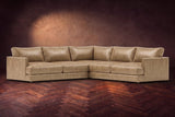 Serena corner sectional in Washed Sand on a walnut herringbone floor, three-quarter view.