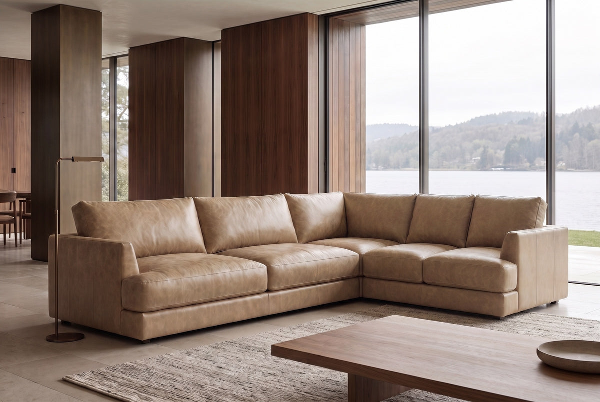 The Serena corner sectional in a wood-panelled room with floor-to-ceiling windows onto a lake, a walnut coffee table in front. Shown in Washed Sand.
