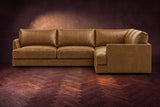 Serena corner sectional in Weathered Saddle on a walnut herringbone floor, seen from the front with the near side on the right.
