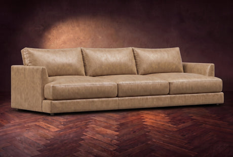 The Serena sofa in Washed Sand distressed full leather on a dark walnut herringbone floor, three-quarter view. Shown in Washed Sand.