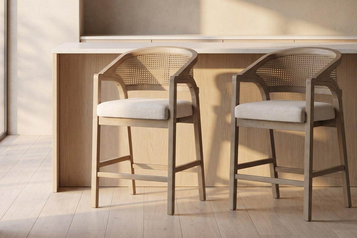 Two Sermoneta counter stools in Natural Ash in front of a pale oak island with a white stone top in a plaster-walled kitchen