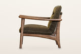 Servigliano accent chair in Green, side view on a warm white studio backdrop: the long flat arm