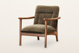 Servigliano accent chair in Green, three-quarter view on a warm white studio backdrop: a brown ash frame with flat wooden arm