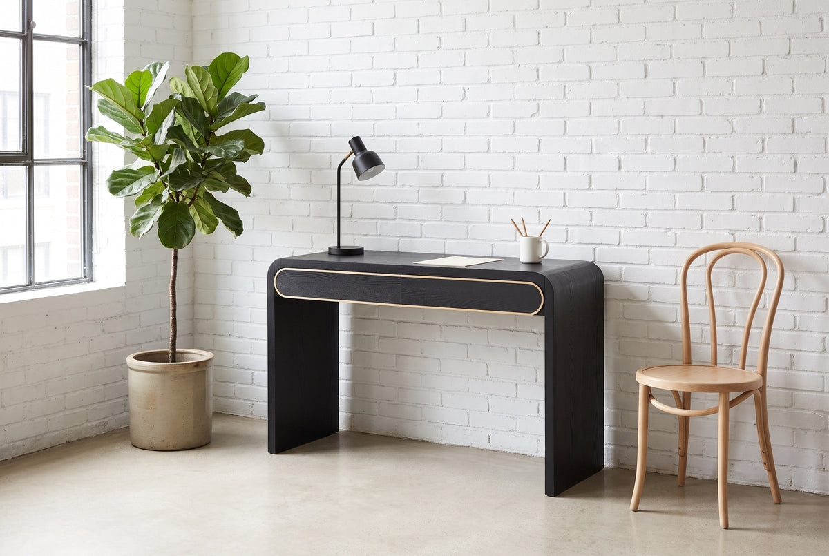 Sestri console table used as a slim desk against a white brick wall in a Montreal loft, a bentwood chair beside it