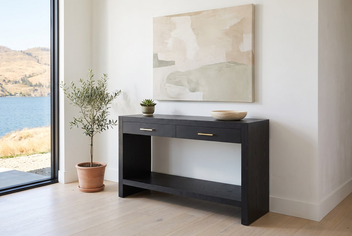 Sibari console table in the white entry of a Kelowna lake house beside a small olive tree, a lake view through the window