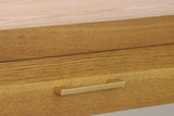 Close-up of a Natural honey-tone drawer front with its gold-tone bar pull under the thick top edge