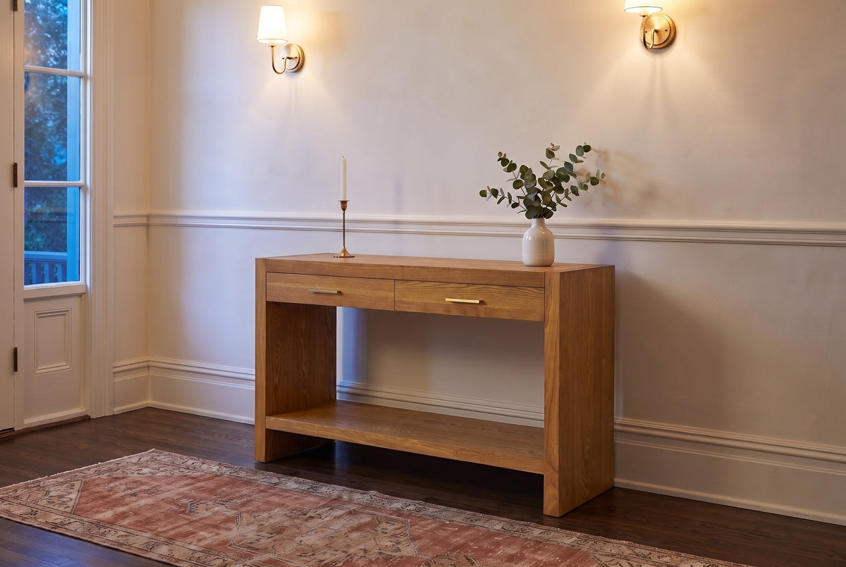 Sibari console table in Natural in a plaster entry hall in Victoria at dusk, brass sconces lit