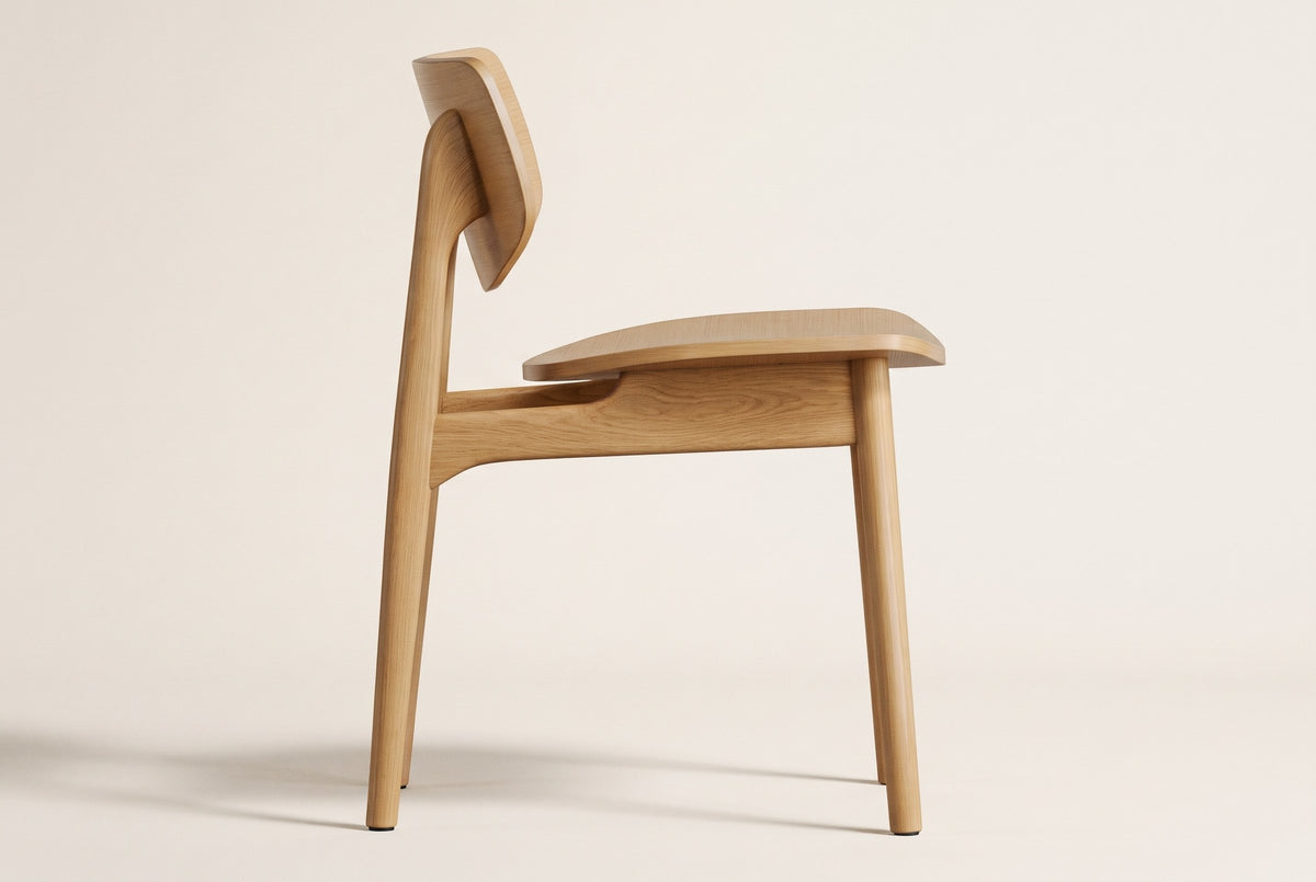 Natural oak Simone dining chair in side view on a plain warm off-white studio backdrop, showing the curved back panel raised on the rear posts, the open gap above the seat, the side rail and four slim legs