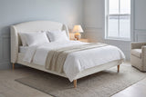 Sirmione boucle wingback bed in a blue-grey bedroom with a window over the harbour and a lit lamp