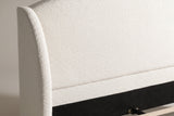 Close-up of a rounded boucle wing beside the plain arched headboard