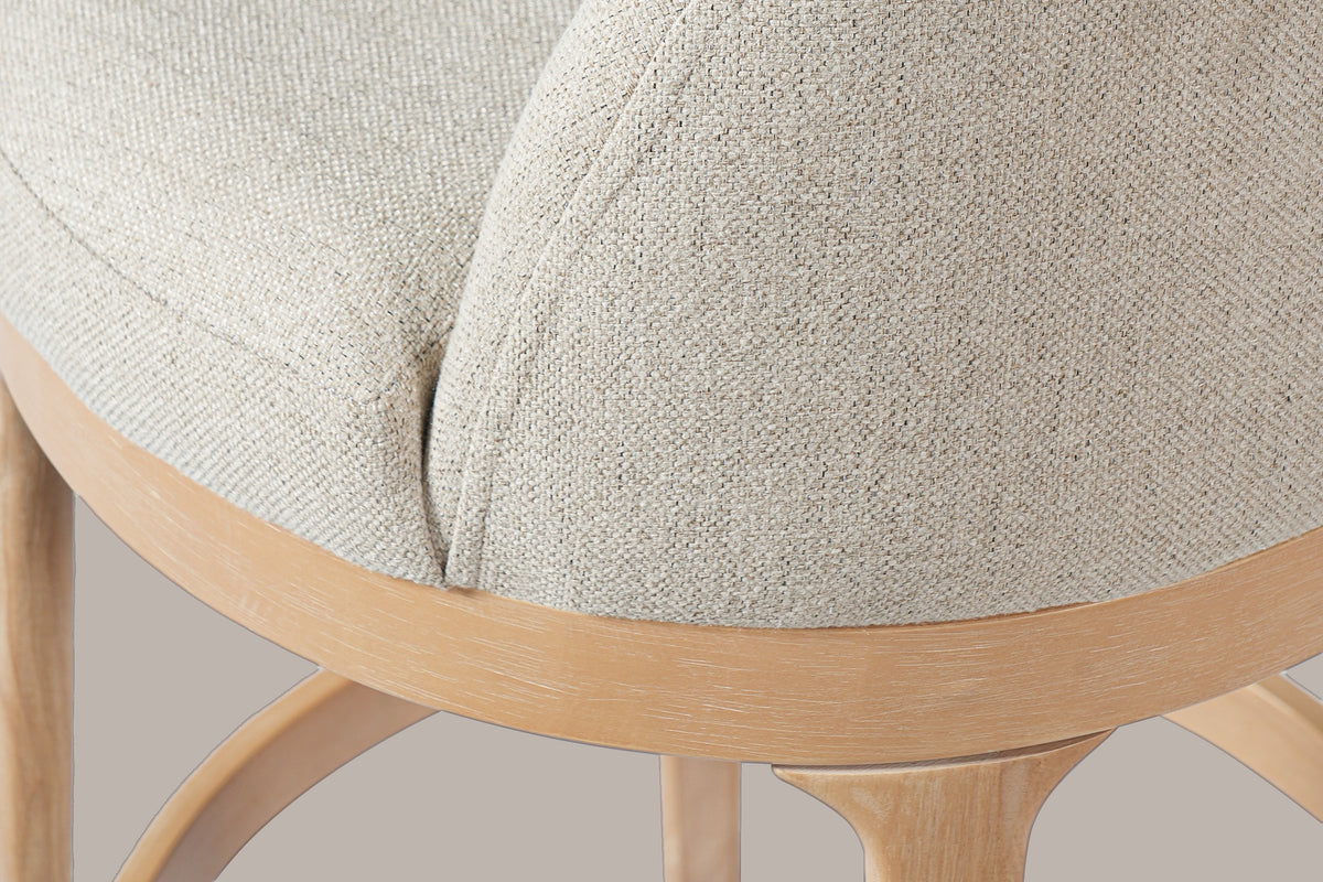 Close-up of the low wrap-around back rising from the seat ring, the curved shoulder of a leg and the footrest ring