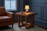 Soave side table beside a cognac leather armchair in a blue-grey Halifax front room at dusk, a small lamp lit on top
