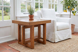 Soave side table beside a white slipcovered armchair in a Victoria garden room, rosemary and a glass of water on top