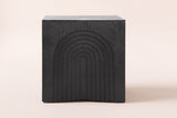 Sondrio side table in Black, straight front view: a stepped arch of seven nested arches carved into the side
