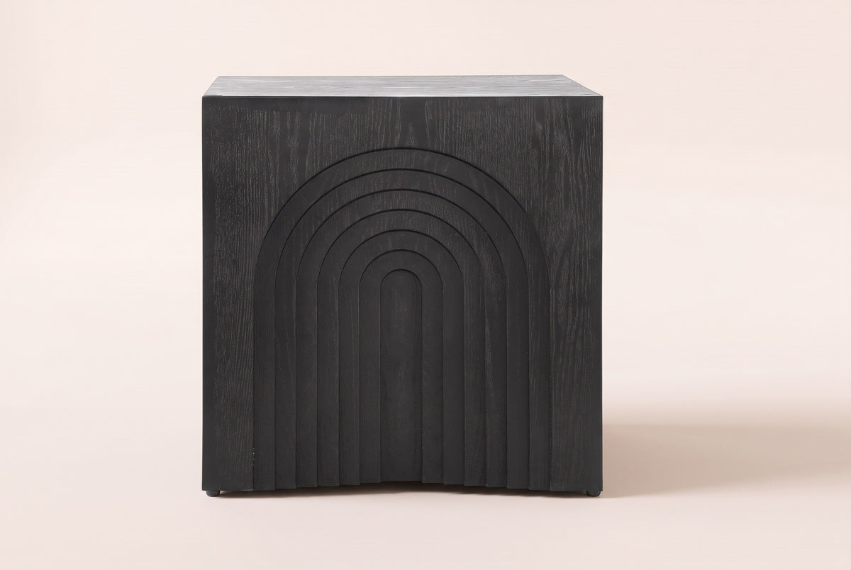 Sondrio side table in Black, straight front view: a stepped arch of seven nested arches carved into the side