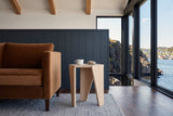 Side view of the Sovana side table in Sandblast White Elm at the arm of a tobacco velvet sofa in a Petty Harbour house