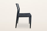 Sperlinga dining chair in black, side view on a warm white studio backdrop: the rear leg runs up into the curved back post