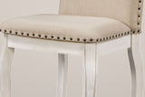 Close-up of a Spilamberto chair: a beige fabric seat edged with a row of antique-bronze nailheads