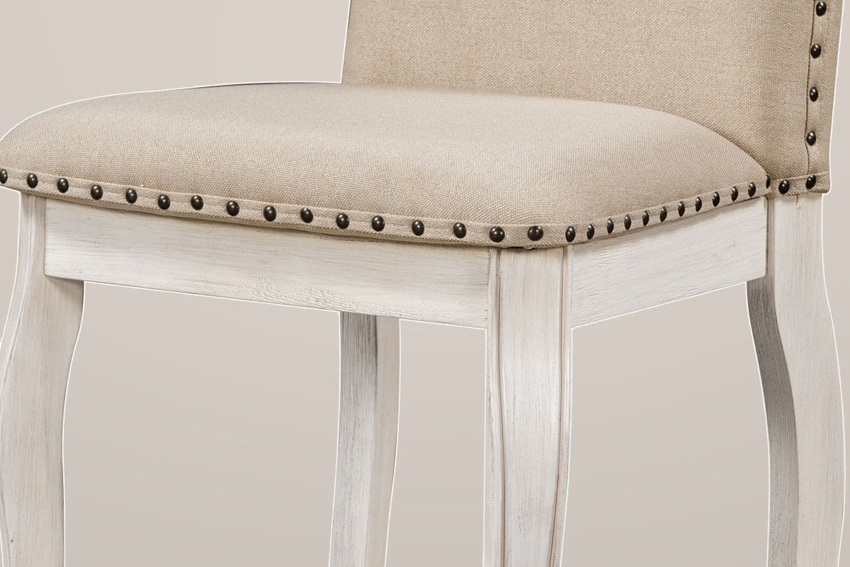 Close-up of a Spilamberto chair: a beige fabric seat edged with a row of antique-bronze nailheads