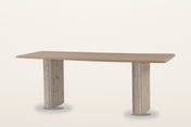 Staffolo marble pedestal dining table in Natural, three-quarter view on a warm white studio backdrop