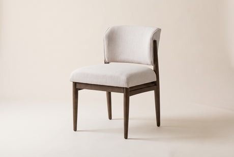 Sutton armless dining chair in Linen Taupe, three-quarter view on a warm off-white studio backdrop
