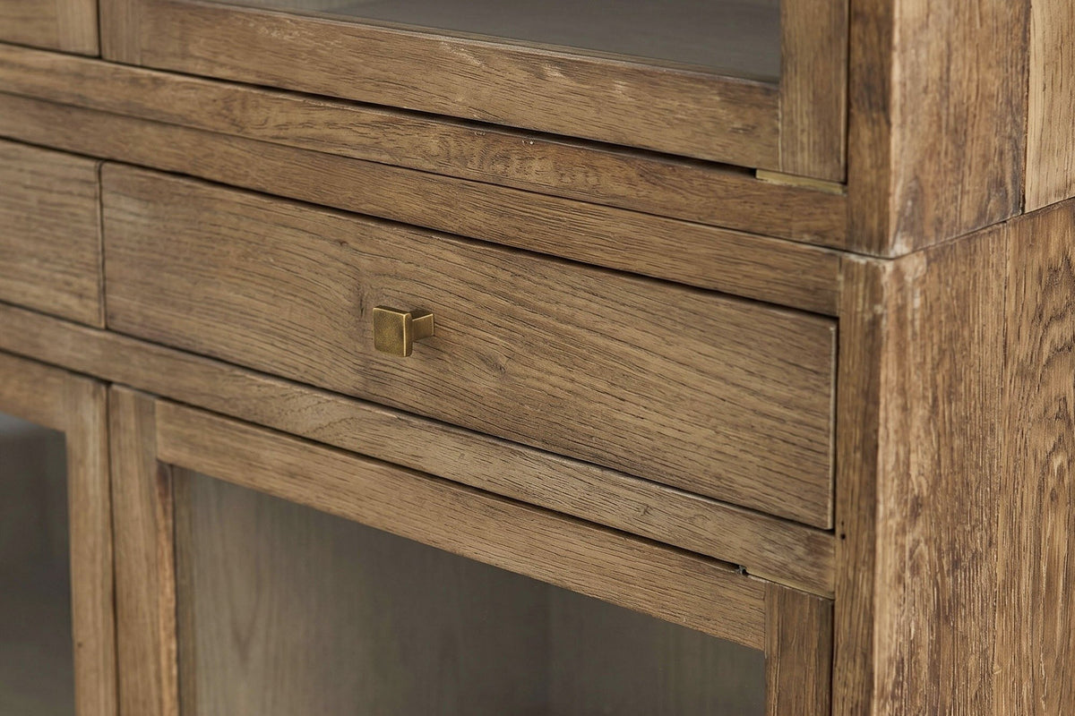 Close-up of a Suvereto drawer in Smokey Grey with its small square gold-finish knob, under a glass door frame