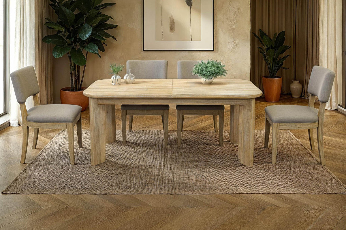 Sylvan dining table with grey upholstered chairs in a warm, plant-filled dining room