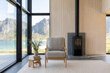 Tagliacozzo accent chair from the front in a Lofoten sea house, by a black wood stove and birch panelling
