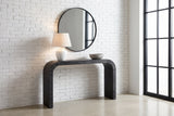 Tarvisio console table in black in a Montreal loft entry, a white lamp and a stone bowl on top, a round mirror above