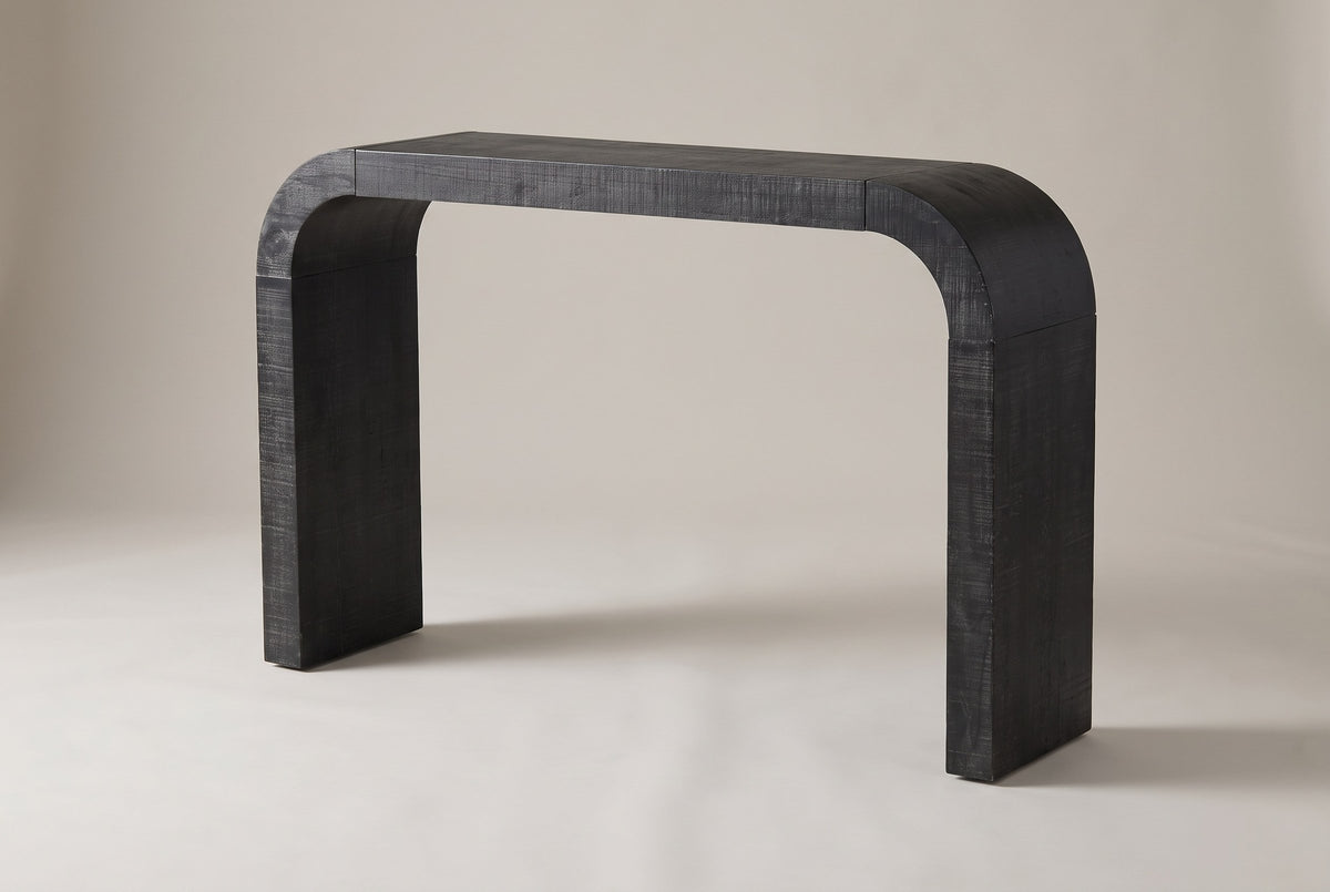 Tarvisio waterfall console table in black, three-quarter view on a warm grey studio backdrop