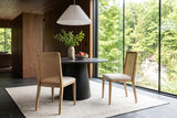 Two Teggiano dining chairs in Natural at a round basalt-top pedestal table in a Rockwood house