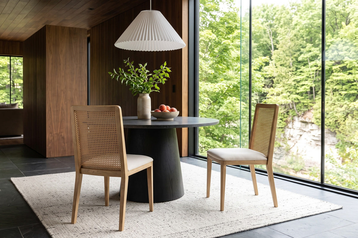 Two Teggiano dining chairs in Natural at a round basalt-top pedestal table in a Rockwood house