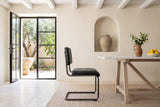 A Tenno dining chair in Black in side profile beside a marble table in a Chania courtyard house