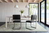 Two Tenno dining chairs in Black seen from behind at a whitewashed ash table in a Gimli lake house, glass to birches