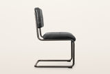 Tenno dining chair in Black, side view on a warm white studio backdrop: one bent tube from the back post to the floor and bac