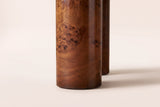 Close-up of one Teramo leg: a 6.22-inch cylinder in the same glossy burl veneer finish, standing on a warm cream backdrop