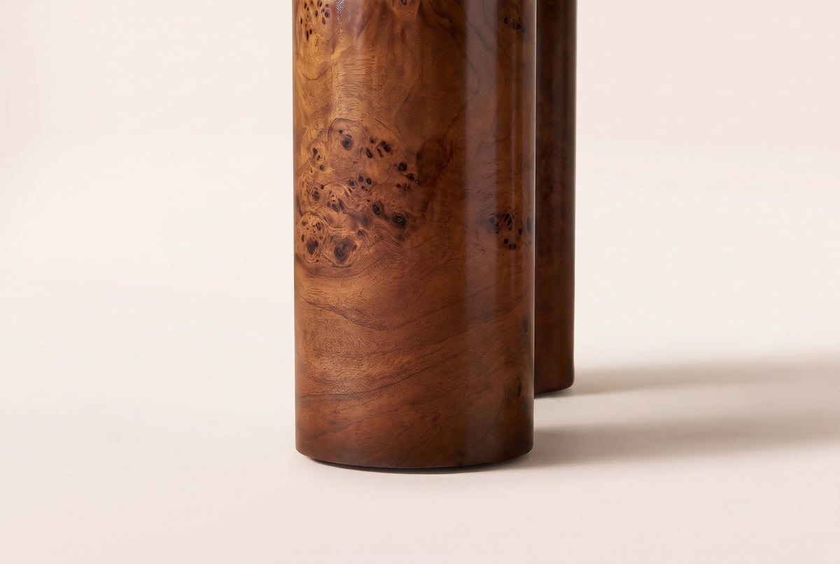 Close-up of one Teramo leg: a 6.22-inch cylinder in the same glossy burl veneer finish, standing on a warm cream backdrop