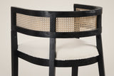Close-up of the back of a Tolmezzo chair: the black wood rails, the woven cane-look band and the ivory boucle-look seat