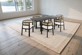 The Tolmezzo dining set on a jute-and-wool rug in a white shiplap Muskoka cottage dining room with a view of the lake